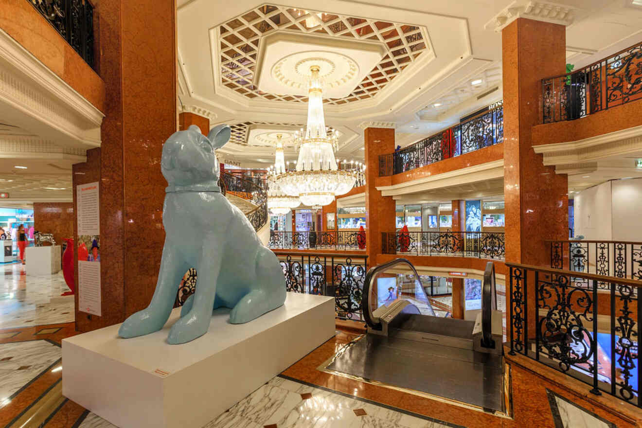 The luxurious interior of Metropole Shopping Center in Monaco, featuring a large blue dog sculpture and a grand chandelier.