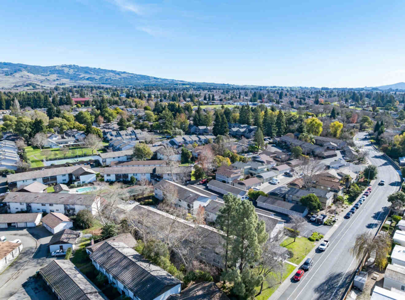 An aerial view of residential houses in Rohnert Park, with a backdrop of hills and a mix of trees.