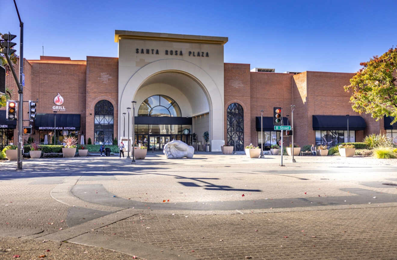 The Santa Rosa Plaza entrance featuring an archway, surrounding shops, and a large sculpture of a hand