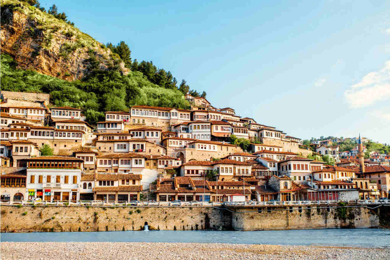 The picturesque hillside town of Berat, featuring rows of white Ottoman-style houses with red roofs stacked along the slope.