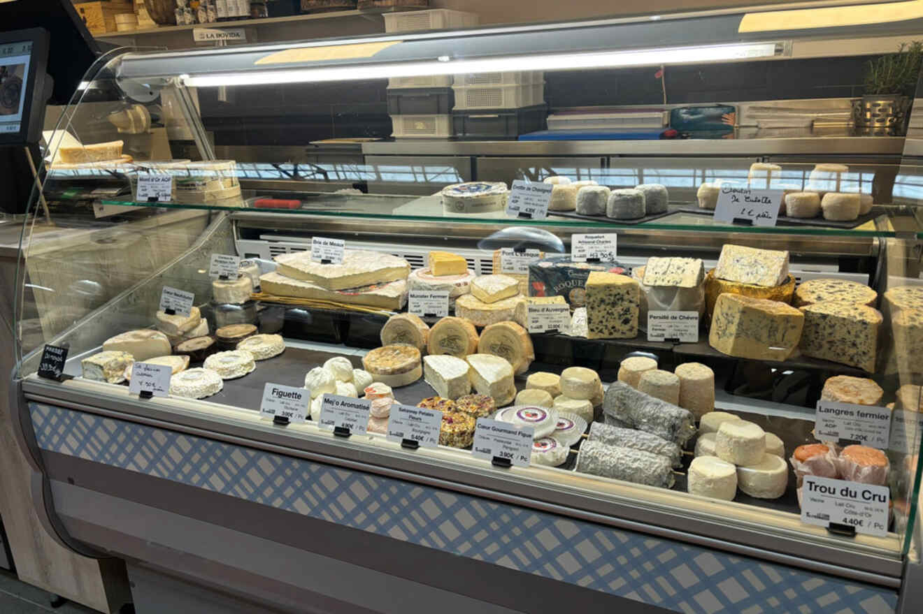 A refrigerated display case filled with a variety of cheeses at Condamine Market in Monaco.