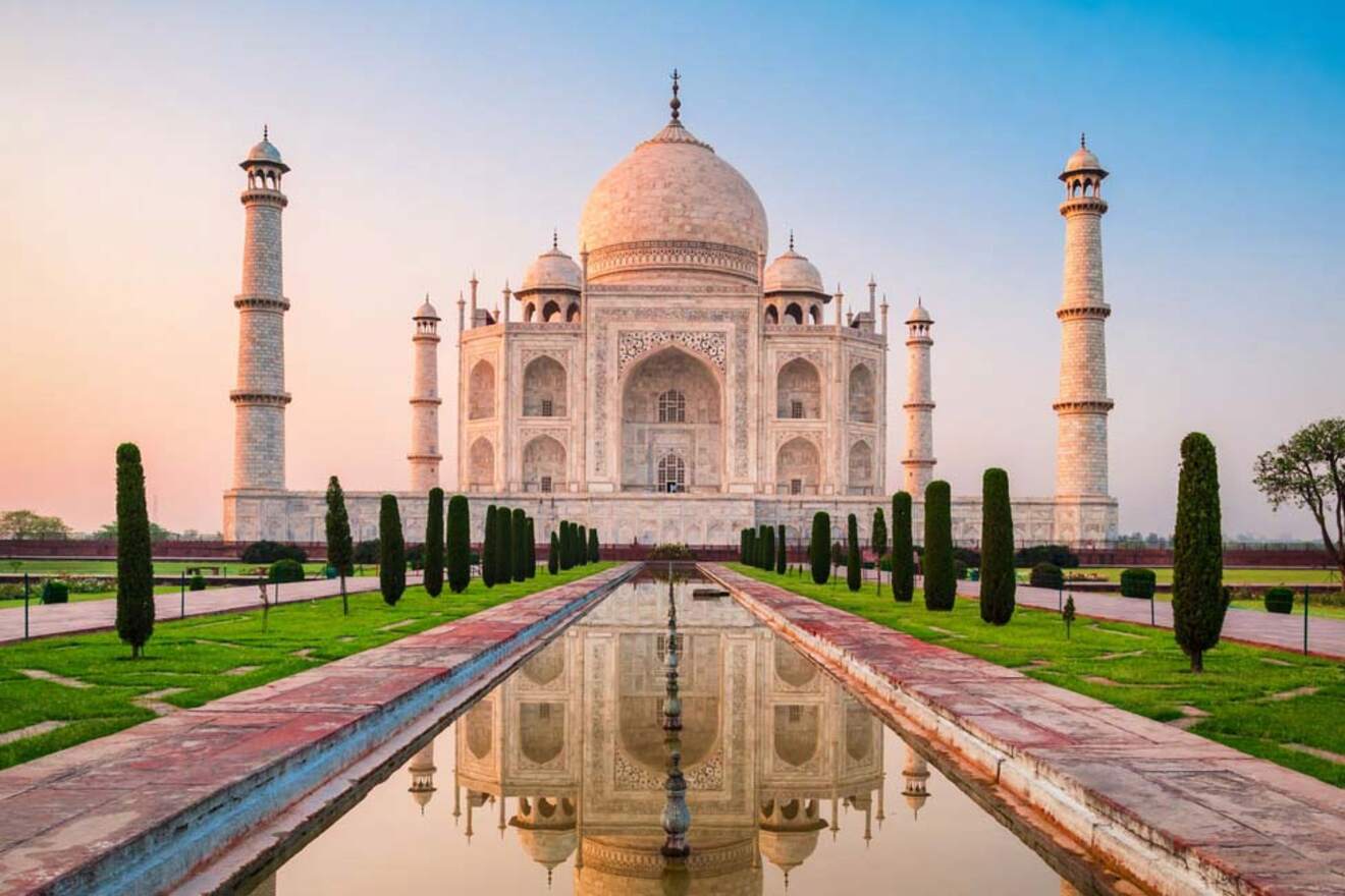 The Taj Mahal in Agra, India, bathed in the soft light of sunrise with its reflection in the water of the front pool.