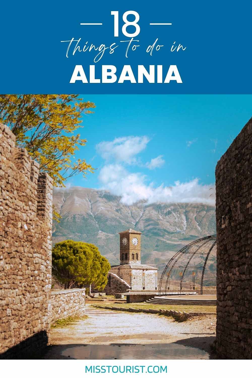 Stone pathway leading to a historic tower with mountains in the background under a blue sky. Text reads: "18 things to do in Albania.