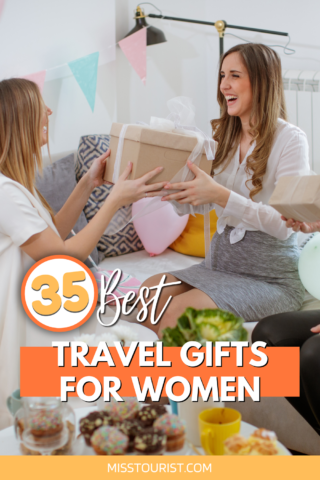 Three women sitting on a couch, exchanging gifts and smiling. The image is overlaid with text reading "36 Best Travel Gifts for Women." Bunting and balloons are visible in the background.