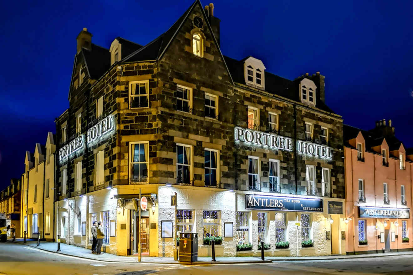 A well-lit hotel named "Portree Hotel" with an adjoining restaurant and bar called "Antlers," located on a street corner at night.