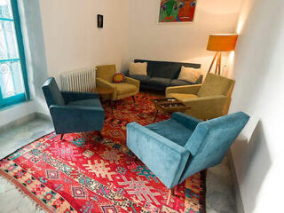 A cozy seating area with modern chairs and a vibrant red patterned rug in a well-lit room.