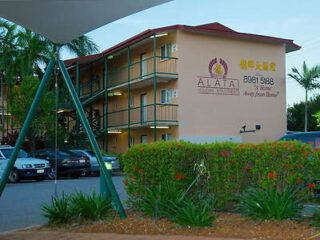 Three-story apartment building with exterior staircases, surrounded by greenery and parked cars. The sign reads "ALATA" along with a phone number and additional text in Asian characters.