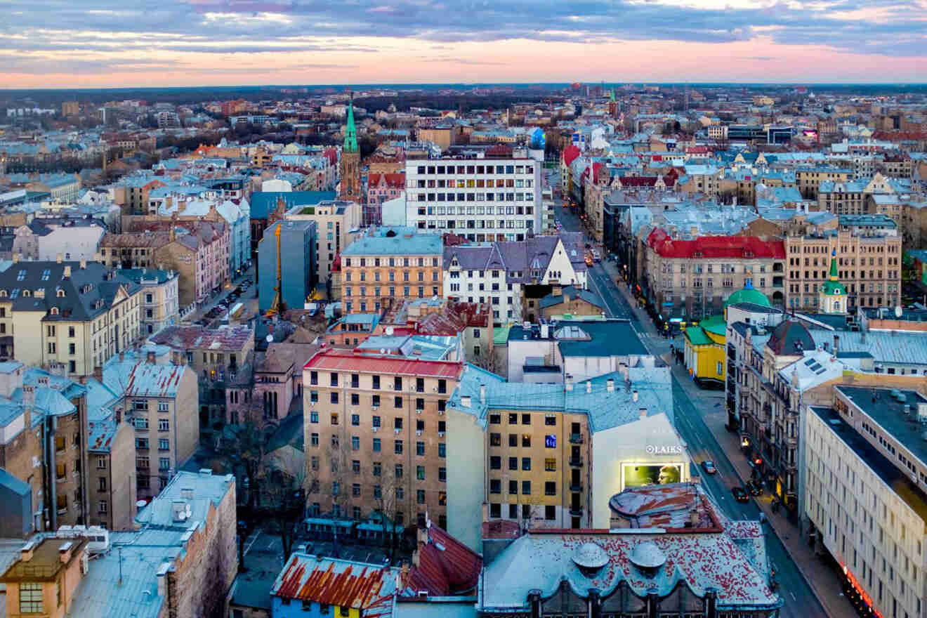 Aerial view of a cityscape at dusk showing rows of buildings with varied architecture, a mixture of modern and older structures, and a main street running through the center.