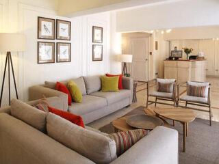 Cozy hotel lobby with beige sofas, colorful cushions, and a warm, inviting atmosphere.