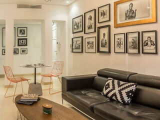 A stylish living area with a black leather sofa, modern art, and framed black-and-white photographs on the wall.