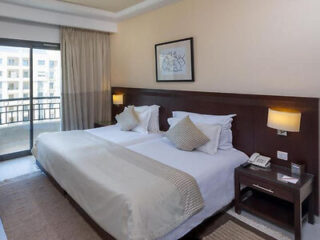 A hotel room with twin beds, a balcony, and warm, neutral tones in the decor.