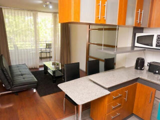 Modern apartment interior with open kitchen, black sofa, dining table with chairs, glass coffee table, and large windows with sheer curtains.