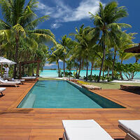 A luxurious outdoor pool surrounded by wooden decking and lounge chairs