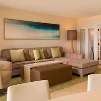 Living room with a beige sectional sofa, green and beige throw pillows, a large floor lamp, abstract artwork on the wall, and a coffee table.