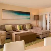 Living room with a beige sectional sofa, green and beige throw pillows, a large floor lamp, abstract artwork on the wall, and a coffee table.
