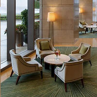 A cozy hotel lounge area with four upholstered chairs arranged around a round coffee table