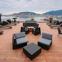 A rooftop terrace with contemporary seating arrangements overlooking a scenic bay and distant mountains