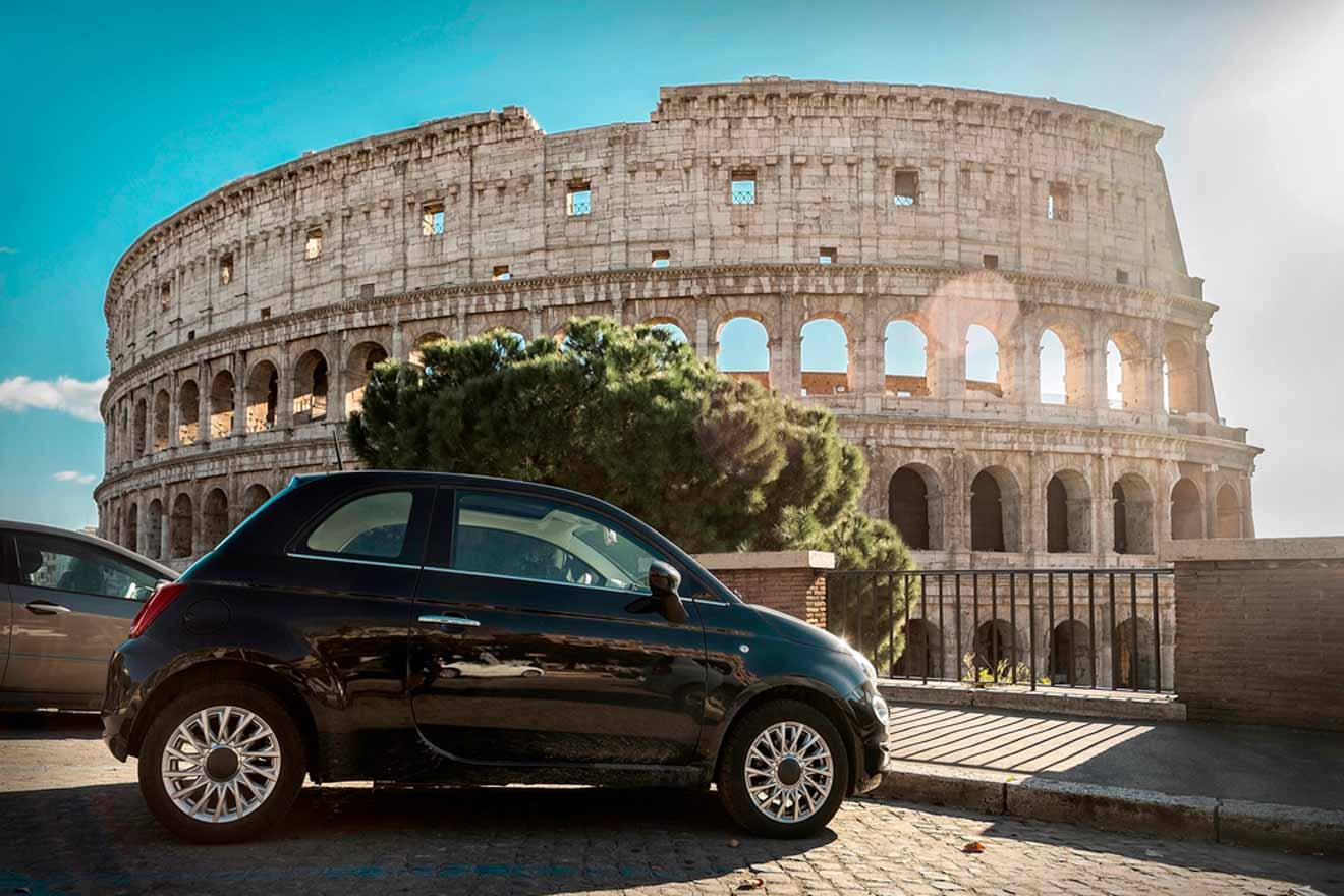 A black car is parked in front of the Colosseum in Rome under a clear sky.