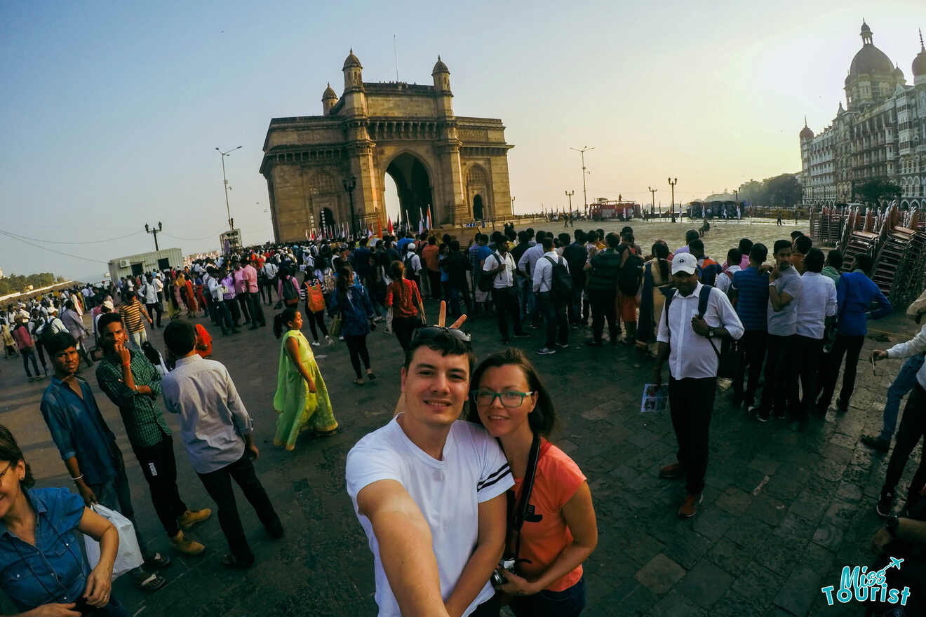 A large crowd gathers near the Gateway of India monument; the founder and her husband in the forefront take a selfie.