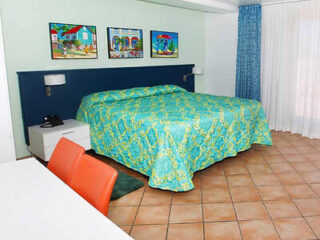 A bright hotel room with a large bed covered in a vibrant blue and yellow patterned bedspread