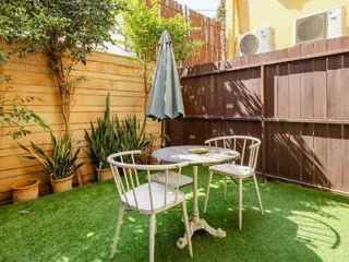 A small outdoor garden patio with a round table, two chairs, and green artificial grass.