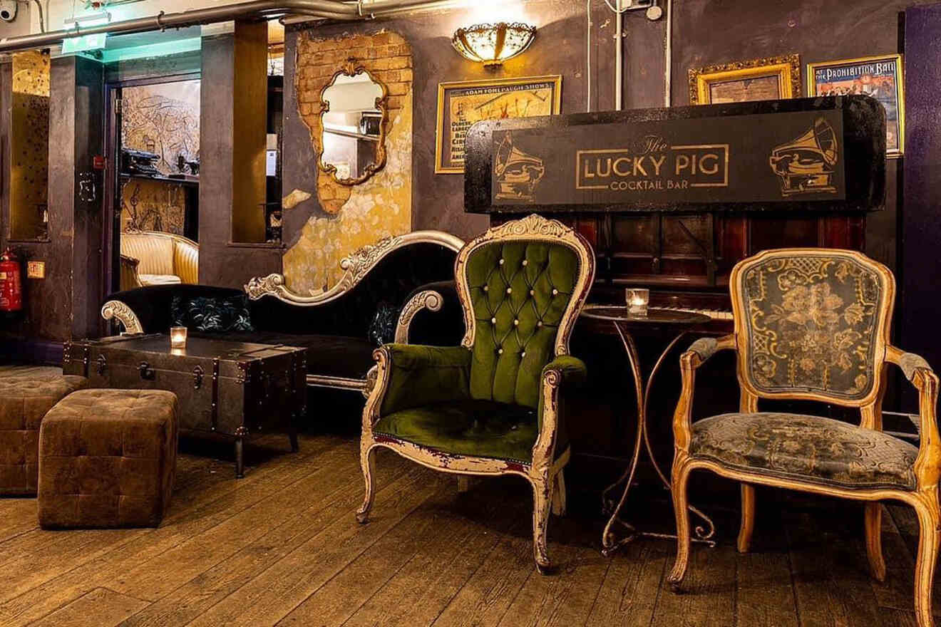 A vintage-themed bar with worn velvet chairs, antique couches, and low lighting, offering a cozy and inviting space.