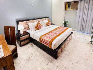 A modern hotel room with a large bed, bright pillows, and a marble floor.