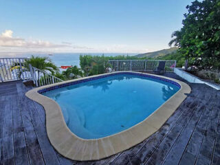 A small, private swimming pool on a wooden deck, overlooking the ocean