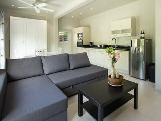 A modern living room and kitchen area with a gray sectional sofa, a black coffee table