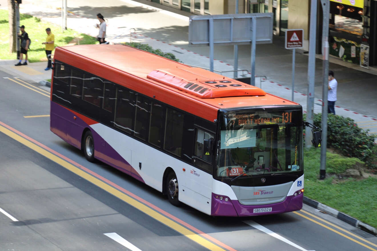 A public transit bus with number 131 on its display is driving on a city street. Several pedestrians are visible in the background.