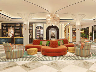 A stylish and vibrant hotel lobby featuring a circular orange couch with colorful pillows