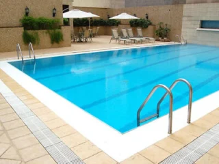 An outdoor swimming pool at the Grandview Hotel Macau, featuring lounge chairs and umbrellas