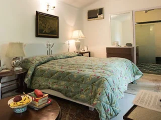 A quaint bedroom with floral-patterned bedding, a side table with fruit, and soft lighting.