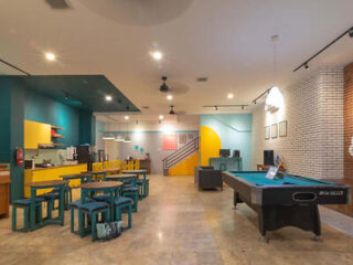 Spacious recreational area featuring a pool table, seating area with tables and benches, and a colorful backdrop including wall art and a staircase.