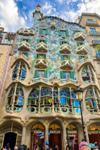 Front view of Casa Batlló, a colorful modernist building in Barcelona, with organic shapes, mosaic façade, and balconies resembling skulls and bones.