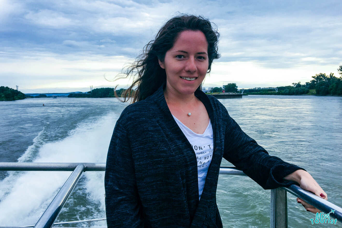 author of the post, wearing a dark jacket over a white shirt, stands on a boat with water and trees in the background.