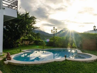 A heart-shaped swimming pool in a grassy backyard with mountains in the background at sunset.