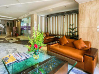 A hotel lobby with leather sofas, a glass coffee table, and decorative plants.