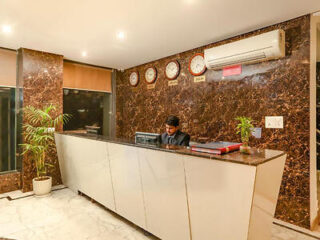 A reception area with a marble counter, clocks showing various time zones, and a receptionist at work.