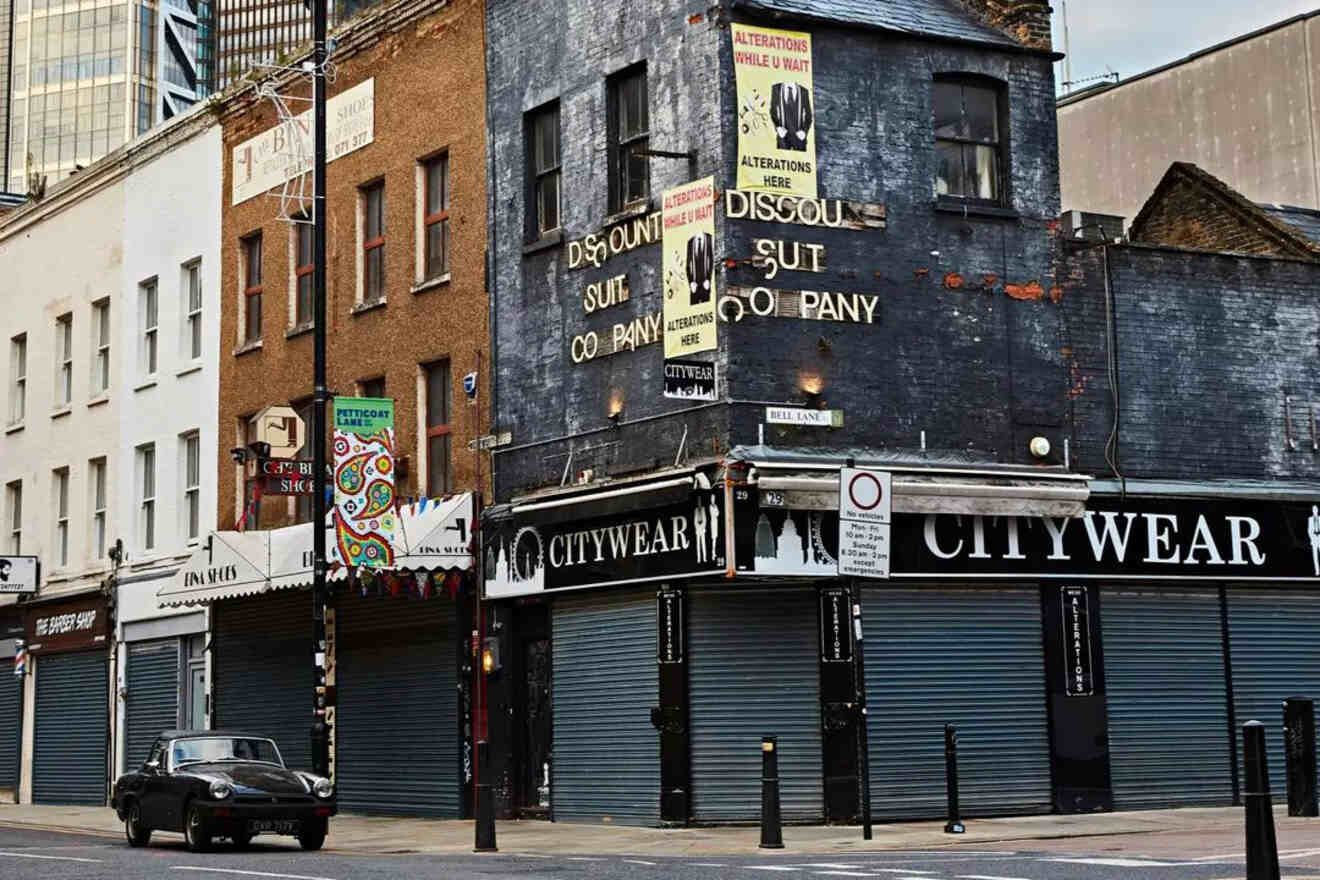 An old building with worn signs advertising "Discount Suit Company" and "Alterations While U Wait," located on a quiet street with closed shopfronts.