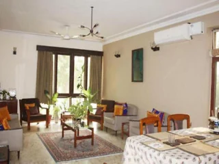 A bright living room with beige walls, large windows, and a variety of seating options.