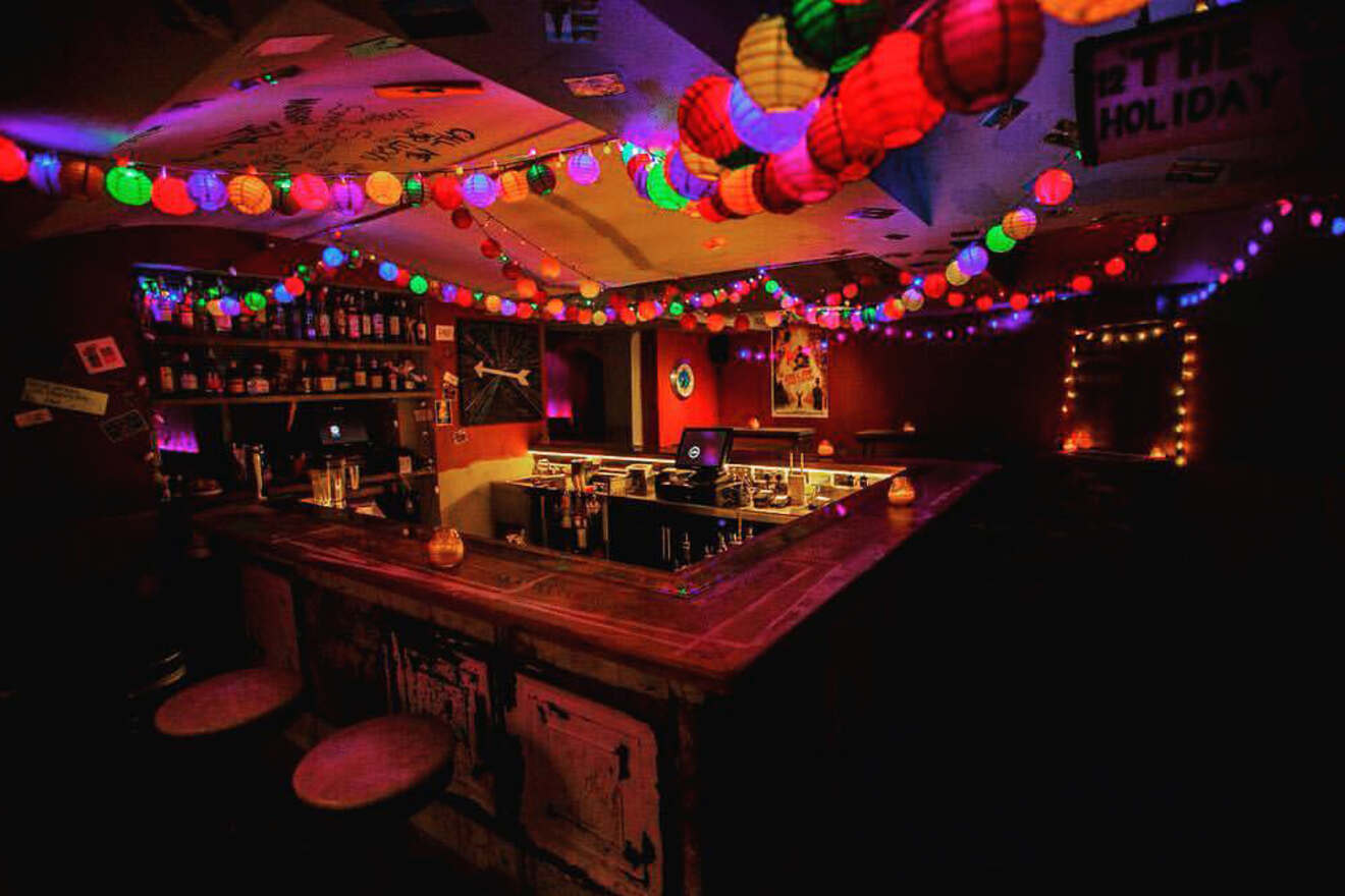 A small bar adorned with colorful lanterns hanging from the ceiling, glowing warmly in an otherwise dim room.