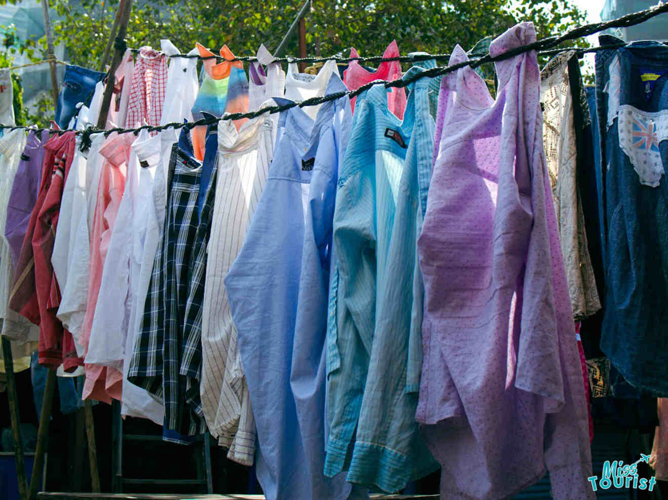 Various colorful shirts and garments hanging on a clothesline outdoors.