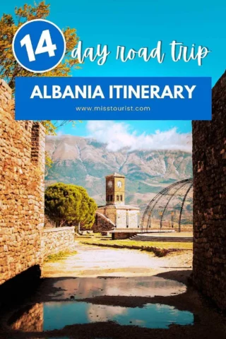 Poster for a 14-day road trip in Albania featuring an itinerary. Image shows a scenic view with a clock tower, stone walls, and mountains in the background. Text overlay includes website misstourist.com.