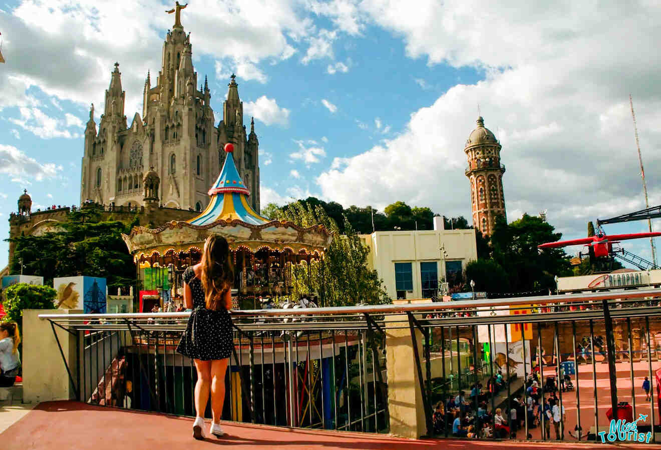 The writer of the post stands on a balcony overlooking a theme park with a carousel and a large church building in the background, under a partly cloudy sky.