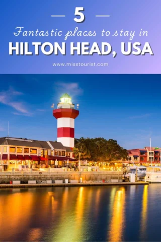 Image showing a lighthouse with surrounding buildings at a waterfront in Hilton Head, USA. Text reads: 