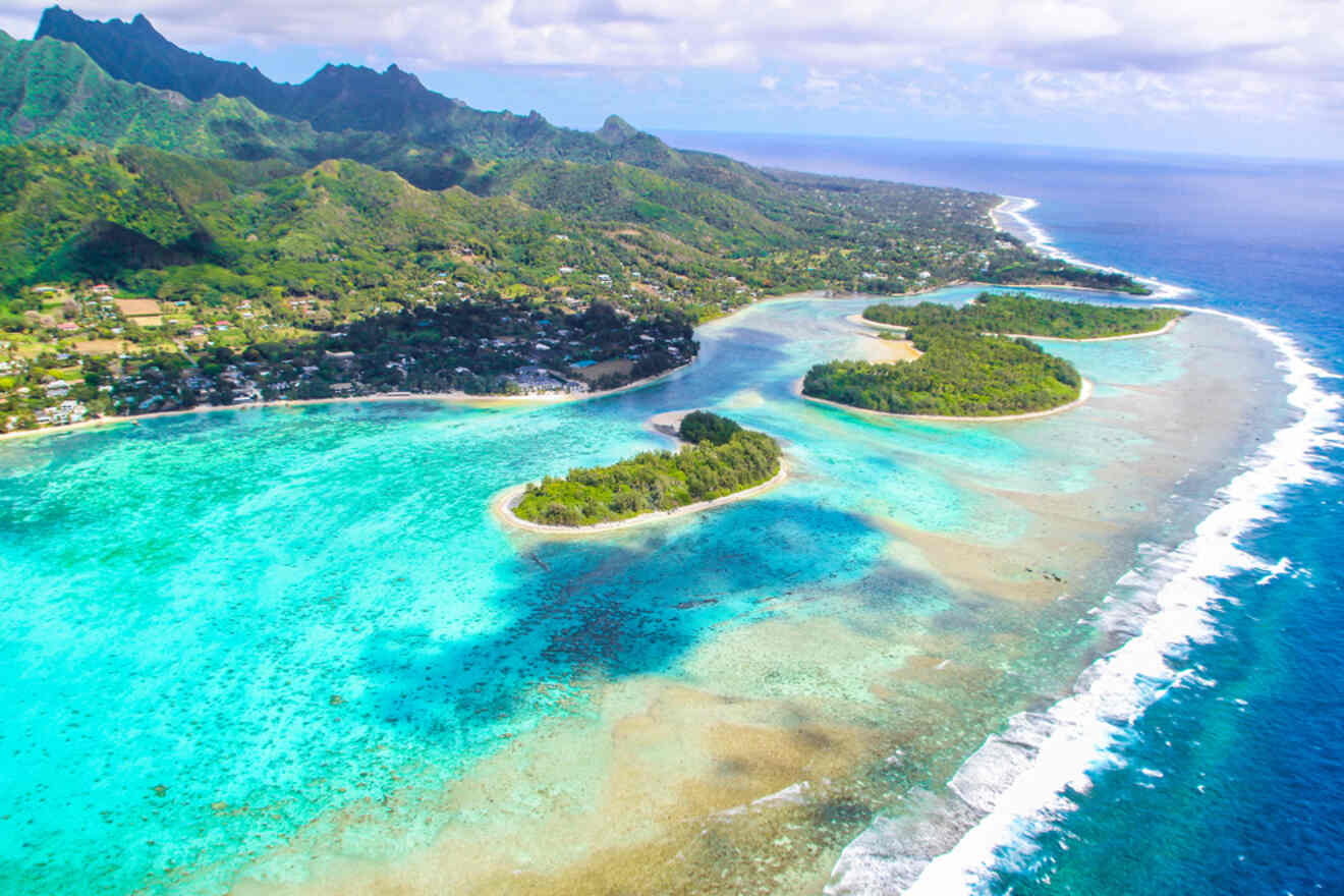 Aerial view of the lush green coastline and turquoise lagoon surrounding the Cook Islands.