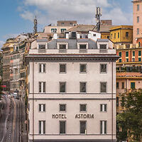 A white building with "Hotel Astoria" written on its facade, surrounded by other multi-story buildings in an urban area.