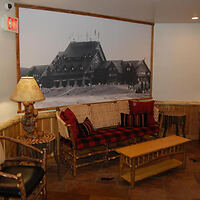 Cozy seating area with a wooden couch, coffee table, and chair, decorated with a large vintage photograph on the wall.