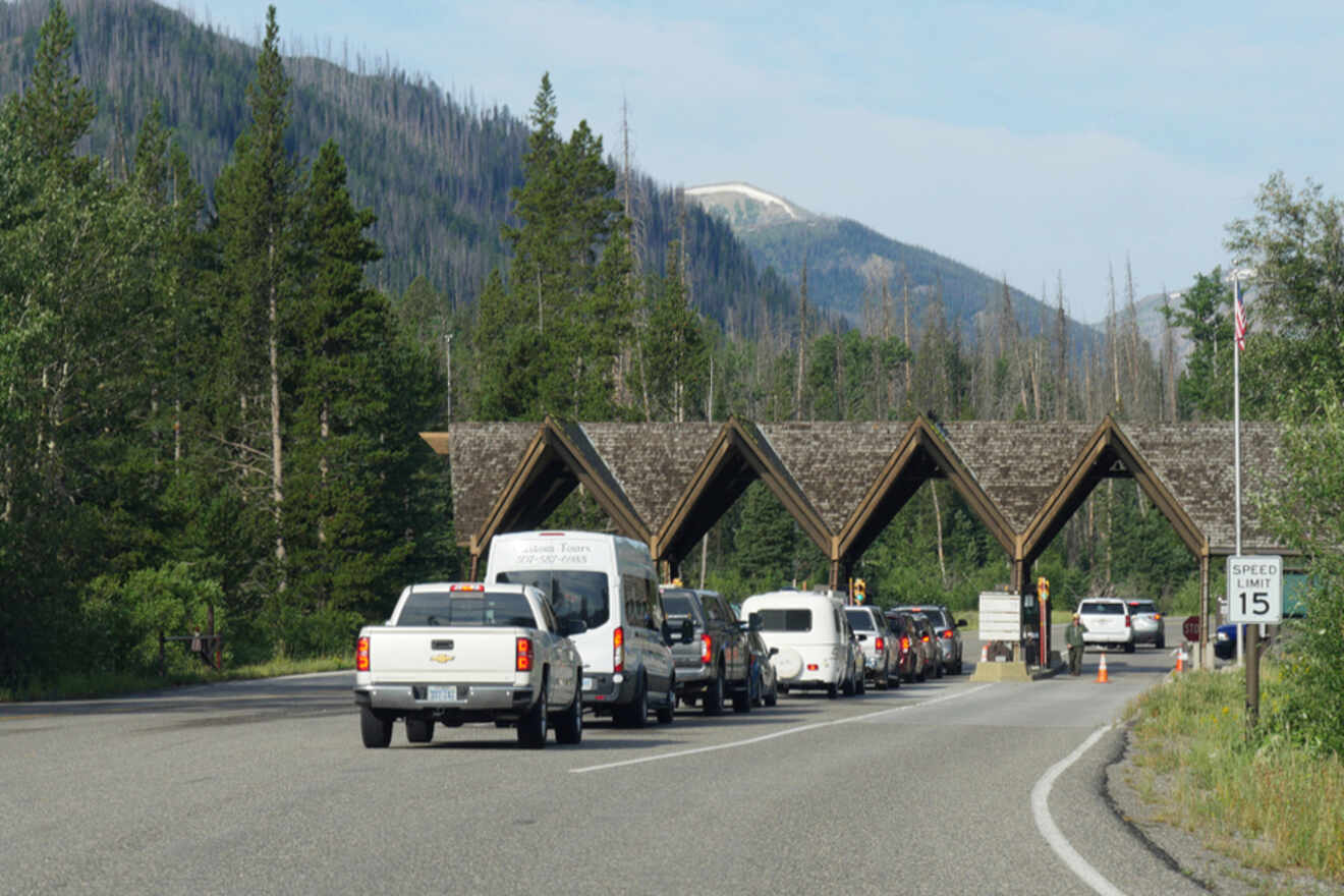 Cars lined up at a national park entrance with a mountainous backdrop.